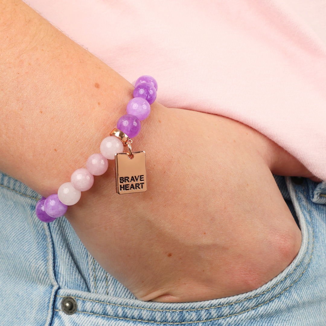 Bracelet with purple and pink beads and 'Brave Heart' charm on wrist
