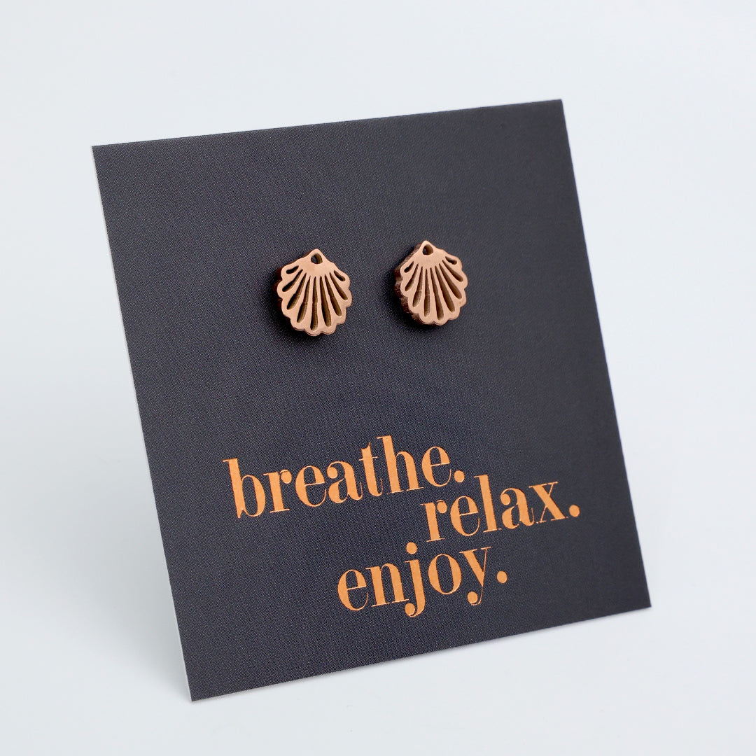 Pair of bronze shell earrings on a black card with 'breathe, relax, enjoy' text.