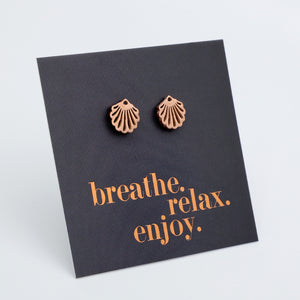 Pair of bronze shell earrings on a black card with 'breathe, relax, enjoy' text.