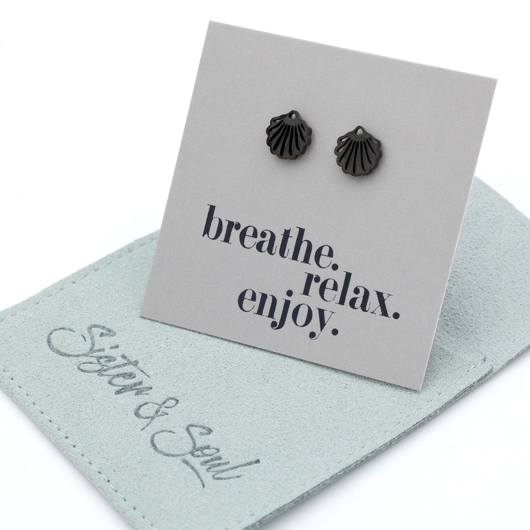 Black shell-shaped earrings on a card with 'breathe. relax.