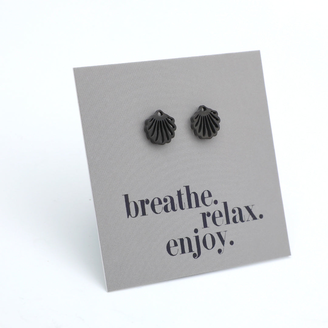 Black shell-shaped earrings on a gray card with 'breathe. relax. enjoy.' text.