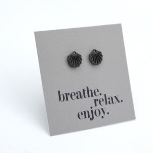Black shell-shaped earrings on a gray card with 'breathe. relax. enjoy.' text.