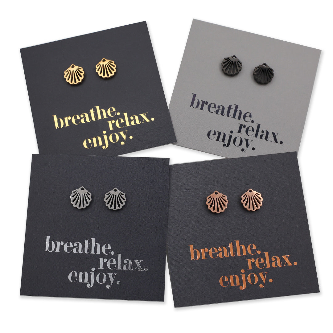 Four pairs of shell-shaped earrings on cards with 'breathe. relax. enjoy.' text.