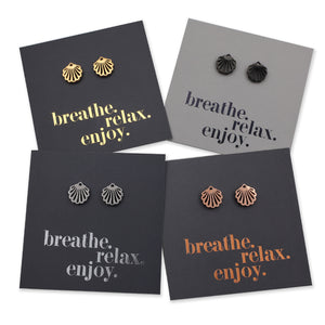Four pairs of shell-shaped earrings on cards with 'breathe. relax. enjoy.' text.