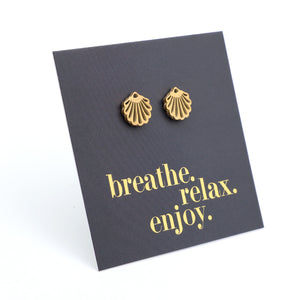Gold shell-shaped earrings on a black card with 'breathe. relax. enjoy.' text.