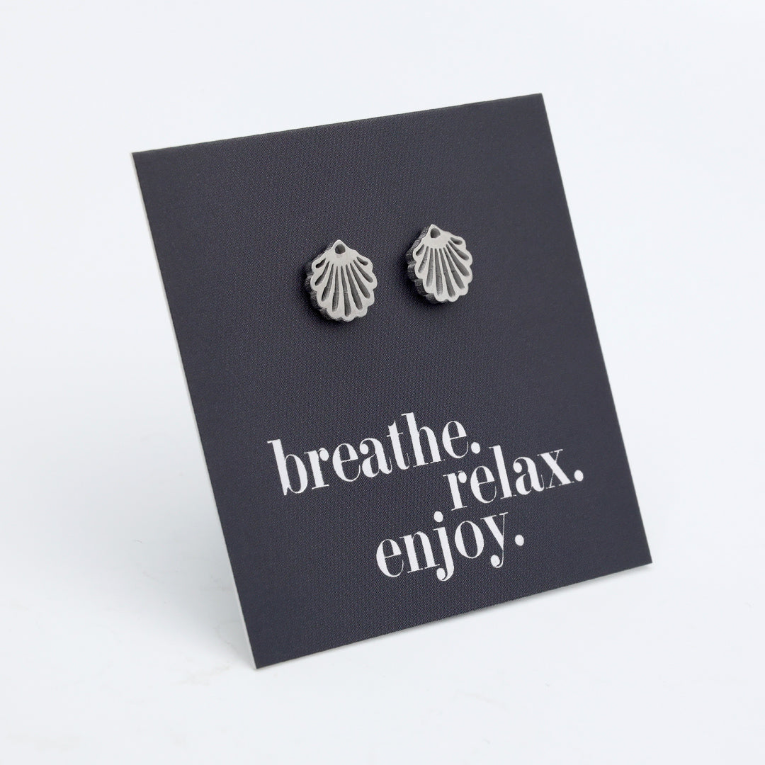 Silver shell earrings on a black card with 'breathe. relax. enjoy.' text