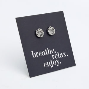 Silver shell earrings on a black card with 'breathe. relax. enjoy.' text