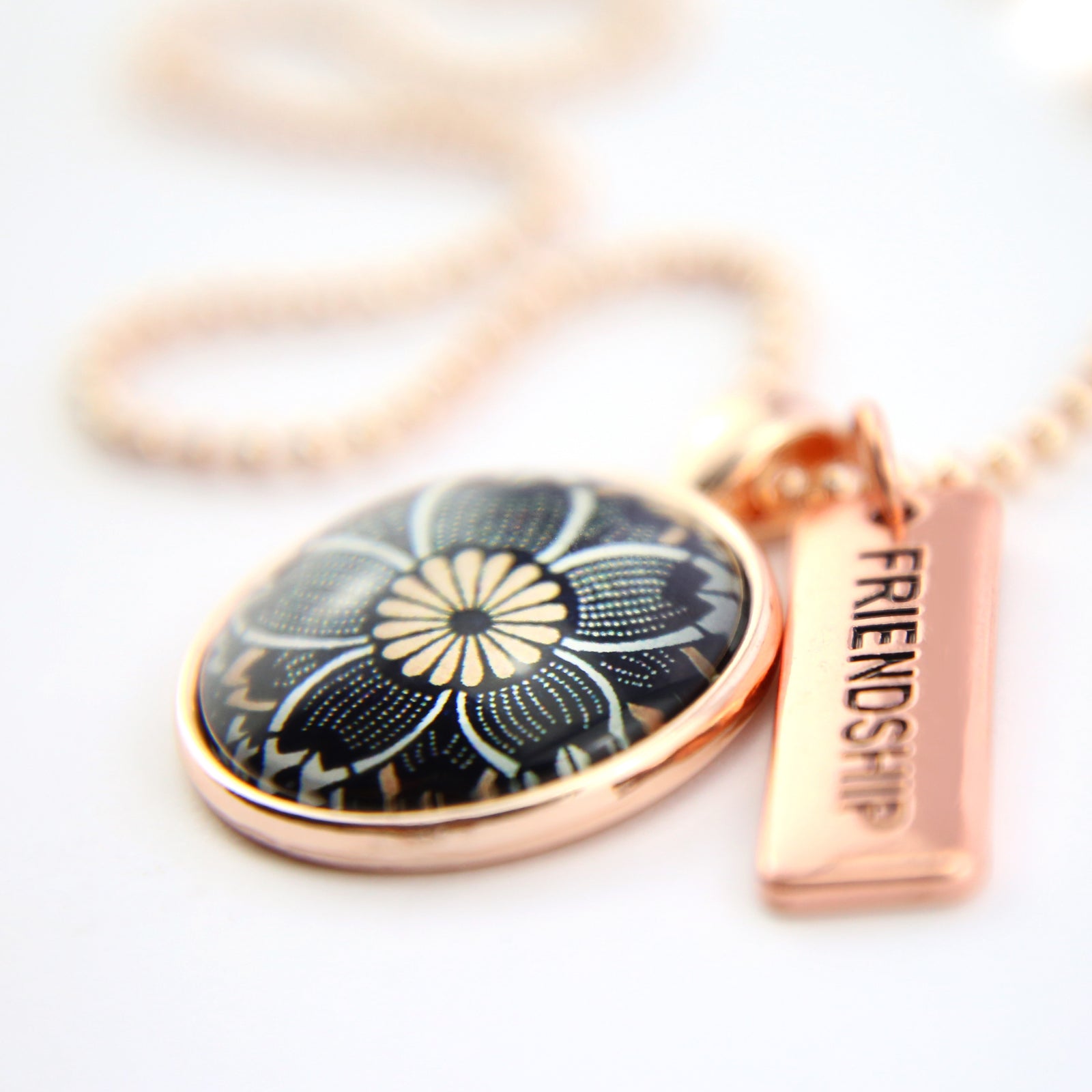 Necklace with floral pendant and 'Friendship' tag on a white background
