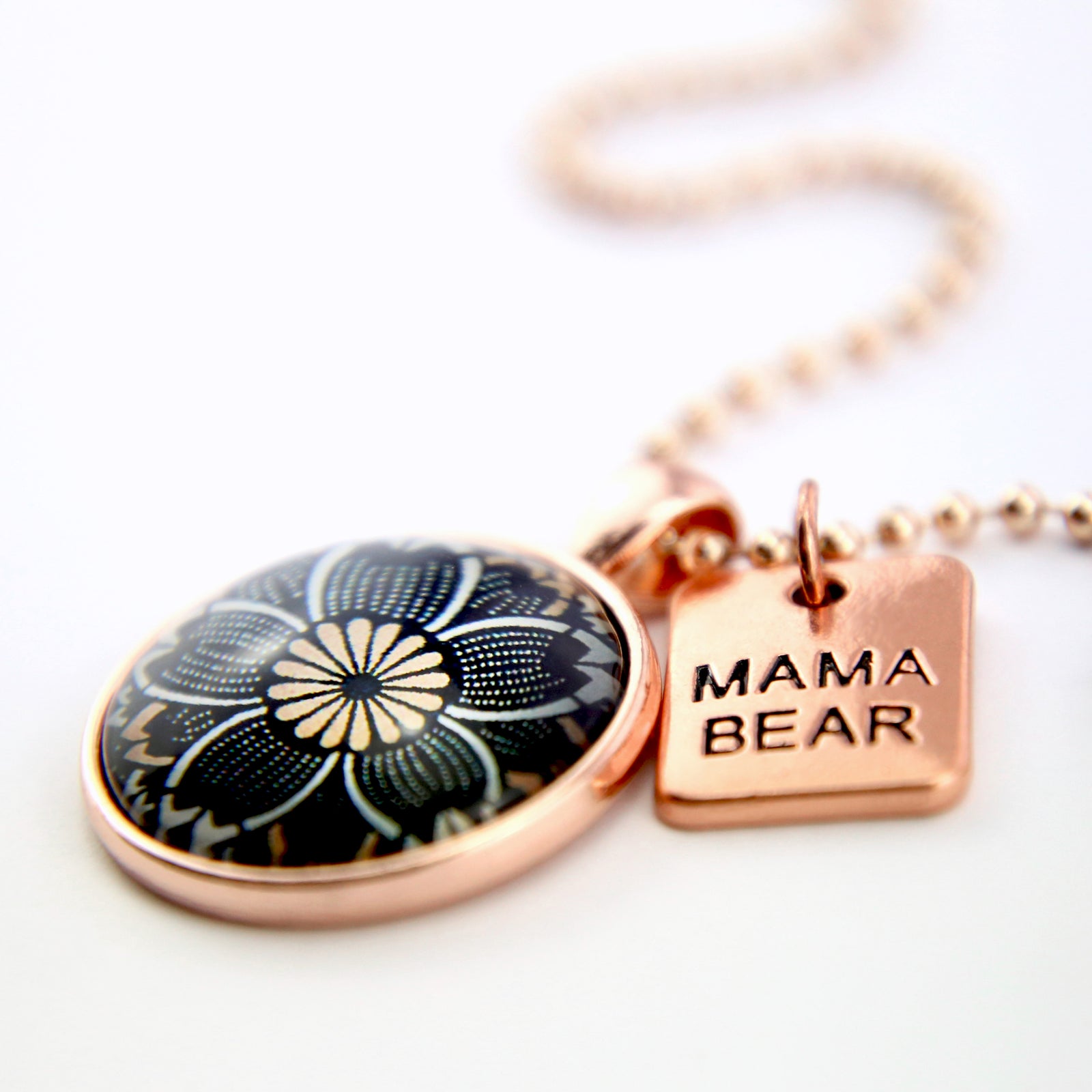 Necklace with floral pendant and 'Mama Bear' tag on a white background
