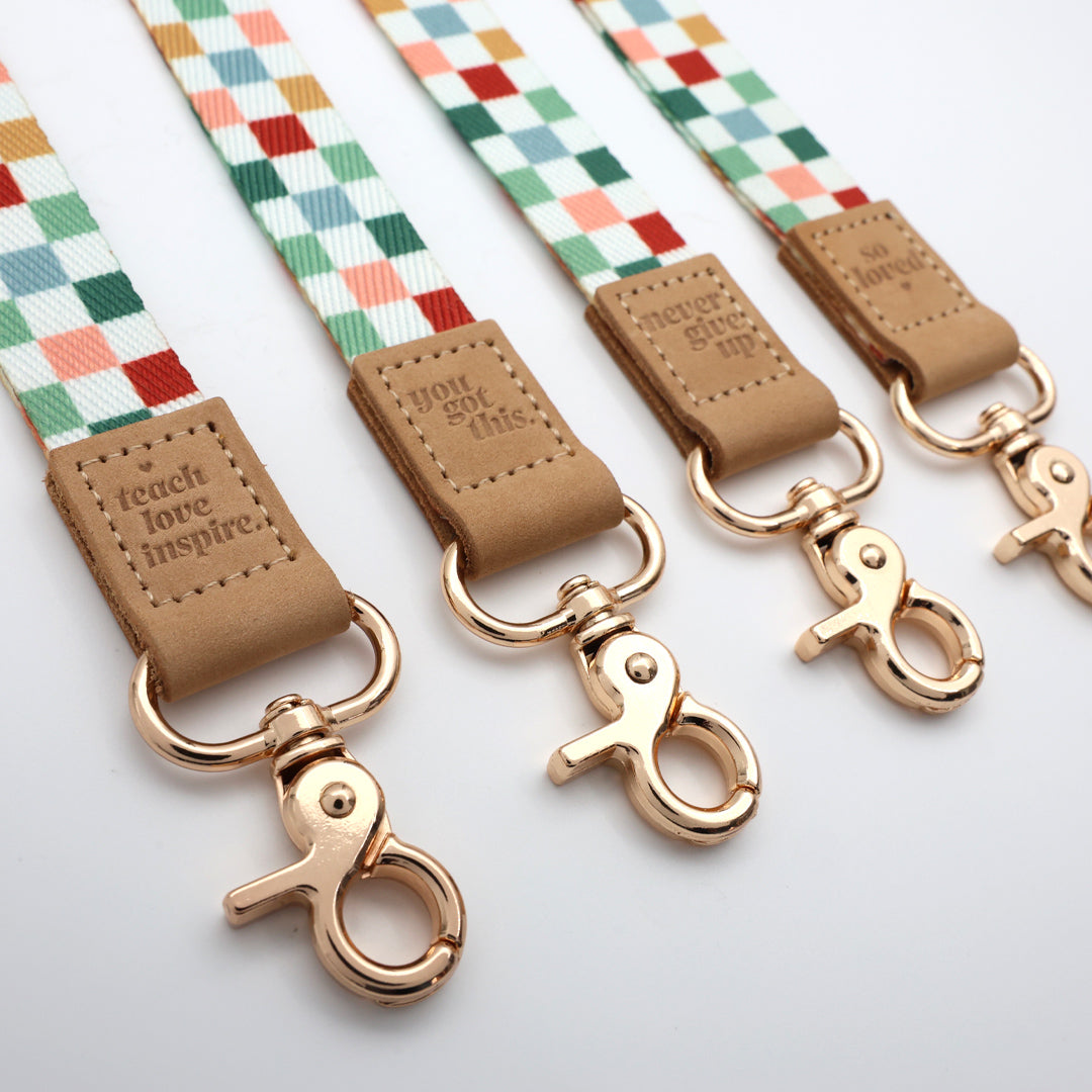Three colorful dog leashes with gold clamps and brown leather ends on a white background.