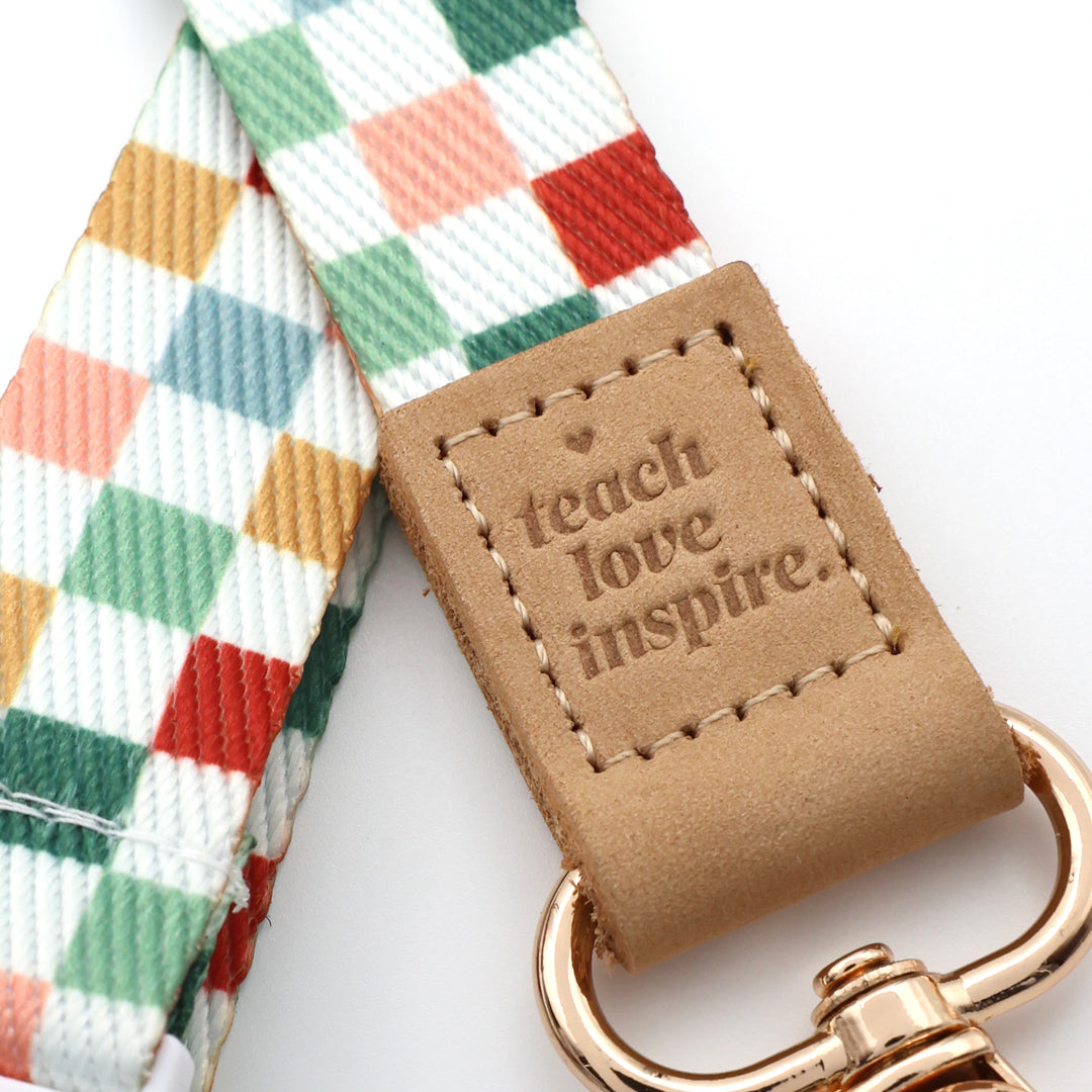 Colorful checkered strap with a leather tag and gold hardware on a white background
