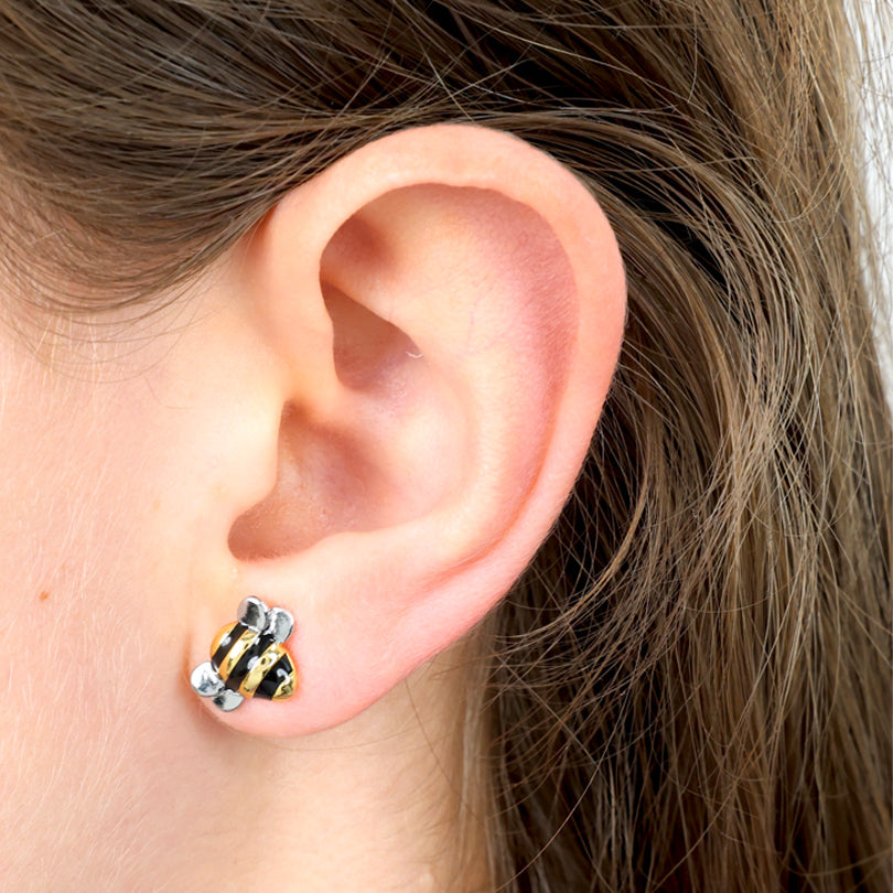 Close-up of an ear wearing a gold and black striped earring.