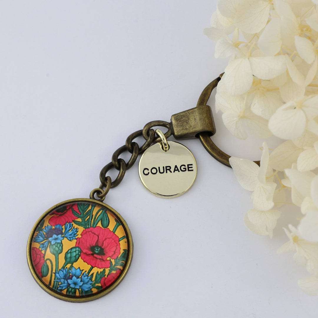 Keychain with floral design and 'COURAGE' tag on a white background