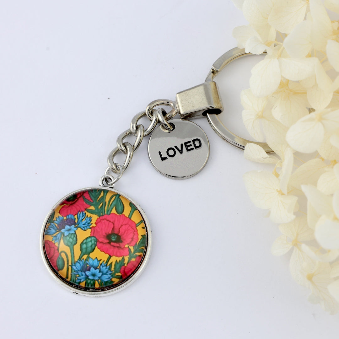 Keychain with floral design and 'LOVED' tag on a white background