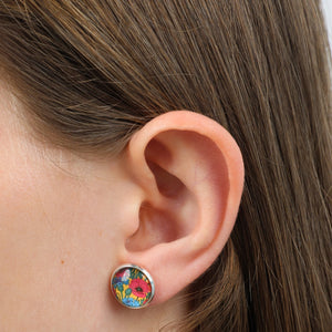 Close-up of an ear wearing a colorful floral earring with brown hair.