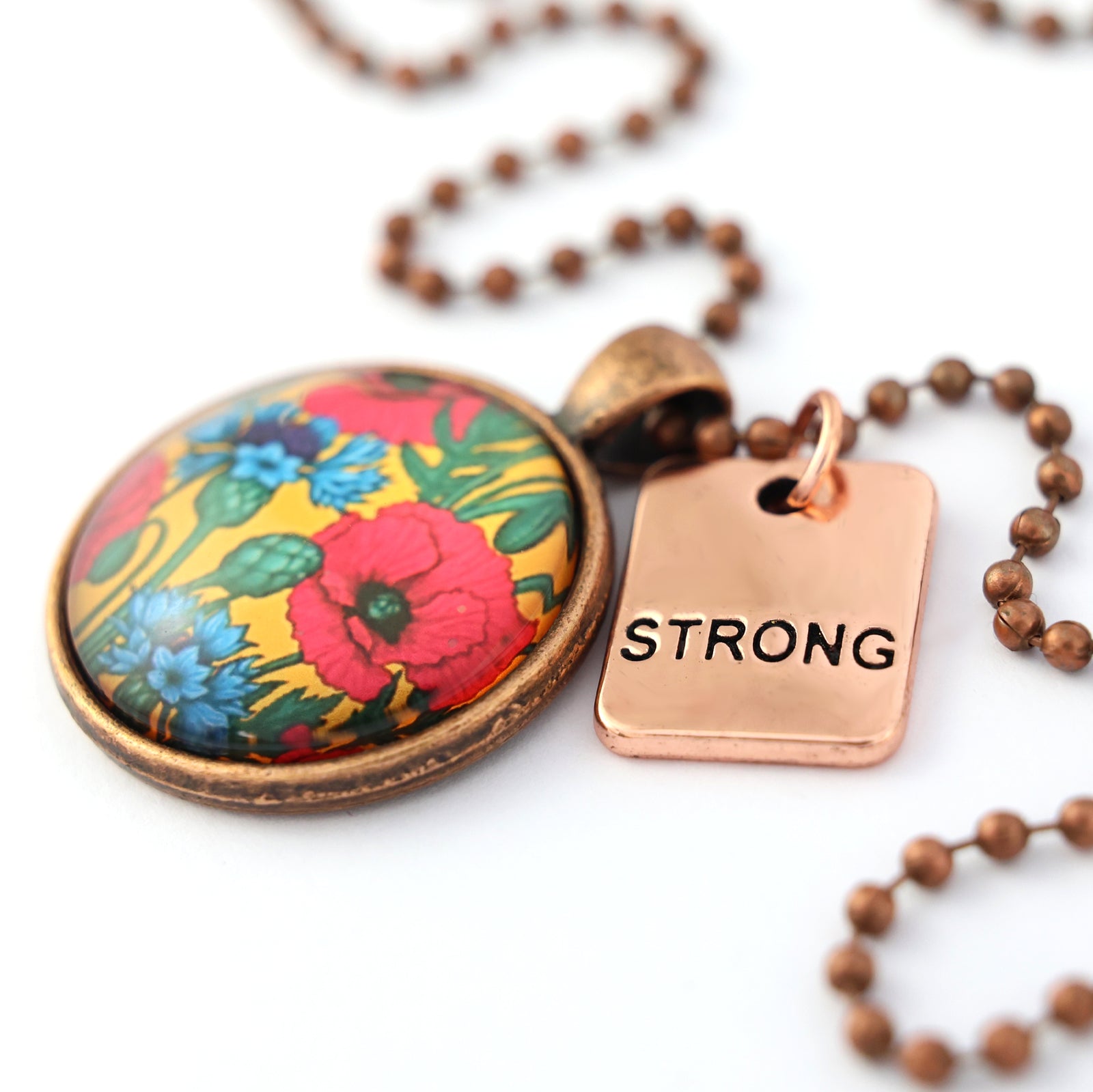Necklace with floral pendant and 'STRONG' tag on a white background