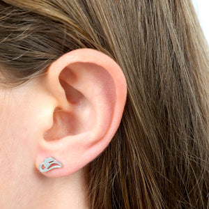 Close-up of an ear wearing a silver cowgirl hat shaped earring 