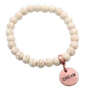 Beaded bracelet with a rose gold 'DREAM' charm on a white background