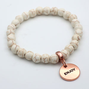 Beaded bracelet with a rose gold charm on a light background