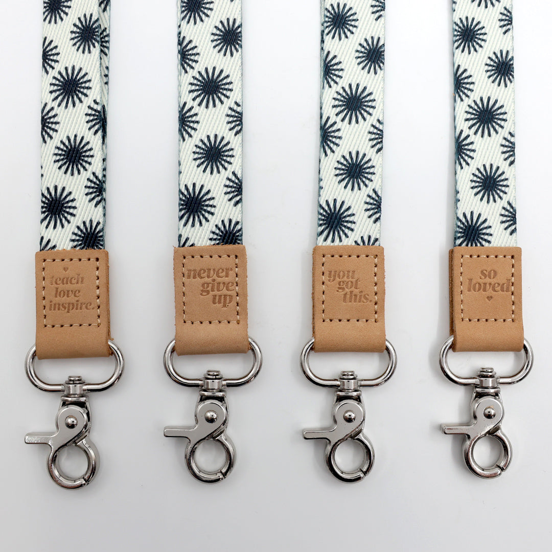 Four lanyards with star pattern and leather tags on a white background