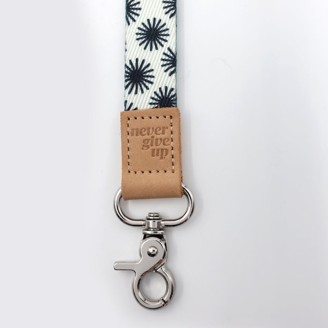 Leash with floral pattern and 'never give up' leather tag on a white background