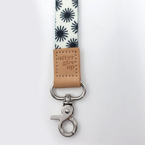 Leash with floral pattern and 'never give up' leather tag on a white background
