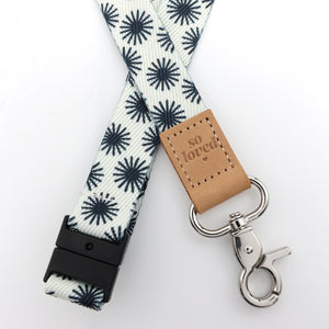 Lanyard with star pattern, brown leather tag, and metal clip on a white background