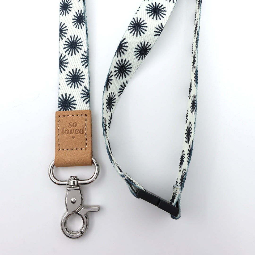Lanyard with black star pattern and 'so loved' leather tag on a white background