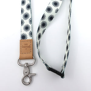 Lanyard with black star pattern and 'so loved' leather tag on a white background