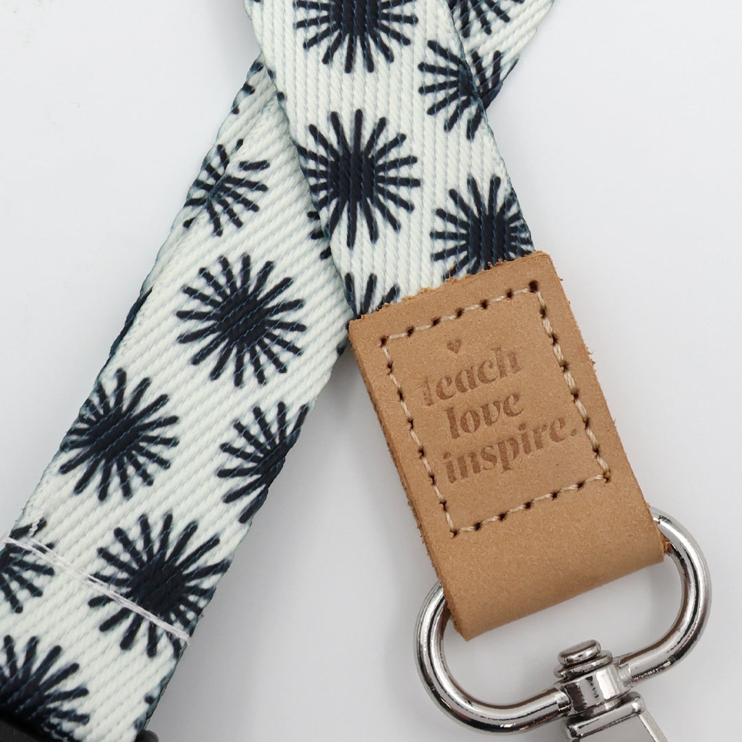 Leash with black star pattern and leather tag with 'teach love inspire' text on a white background