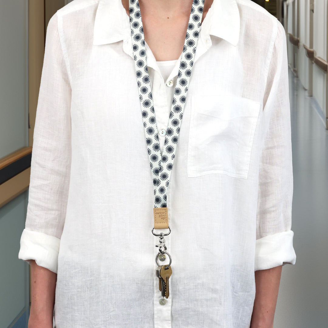 Person wearing a white shirt with a patterned lanyard around their neck.