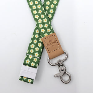 Green floral lanyard with a brown leather tag and metal clip on a white background