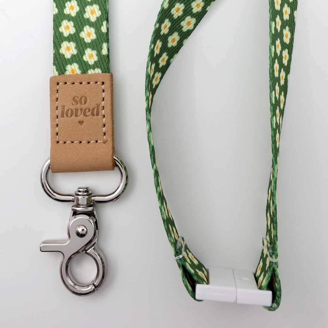 Green floral lanyard with a brown leather tag and metal clip on a white background