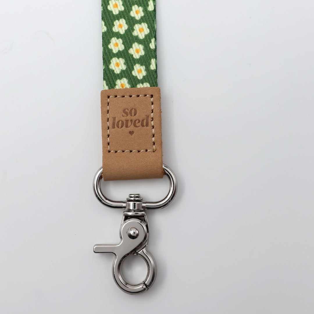 Lanyard with floral pattern and 'so loved' tag on a light gray background