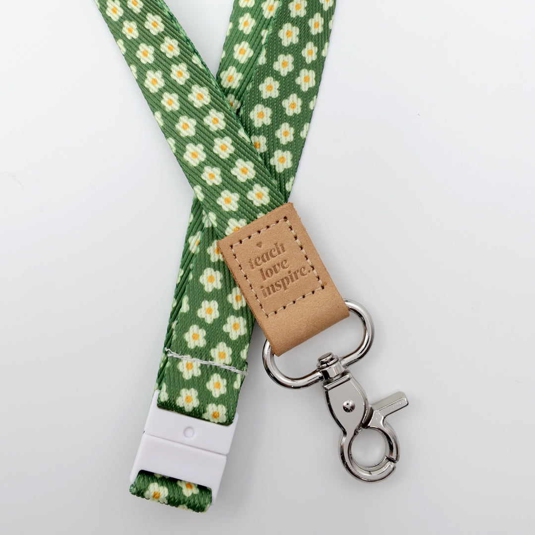 Green floral lanyard with a brown leather tag and metal clip on a white background