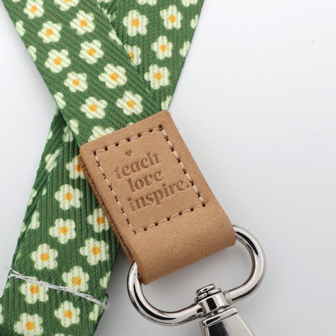 Four green floral patterned straps with brown leather accents and metal clasps on a white background.