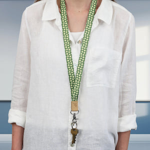 Person wearing a white shirt with a green lanyard and keychain against a neutral background