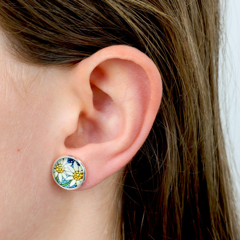 Close-up of an ear wearing a colorful floral stud earring.