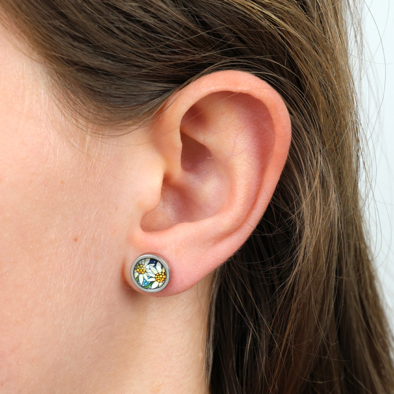 Close-up of an ear wearing a floral stud earring with a white background