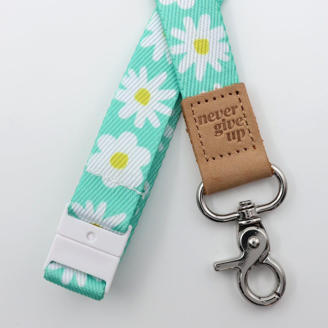 Lanyard with floral pattern and 'never give up' leather tag on a white background