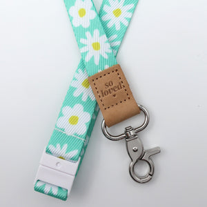 Floral lanyard with a brown leather tag and metal clip on a light gray background
