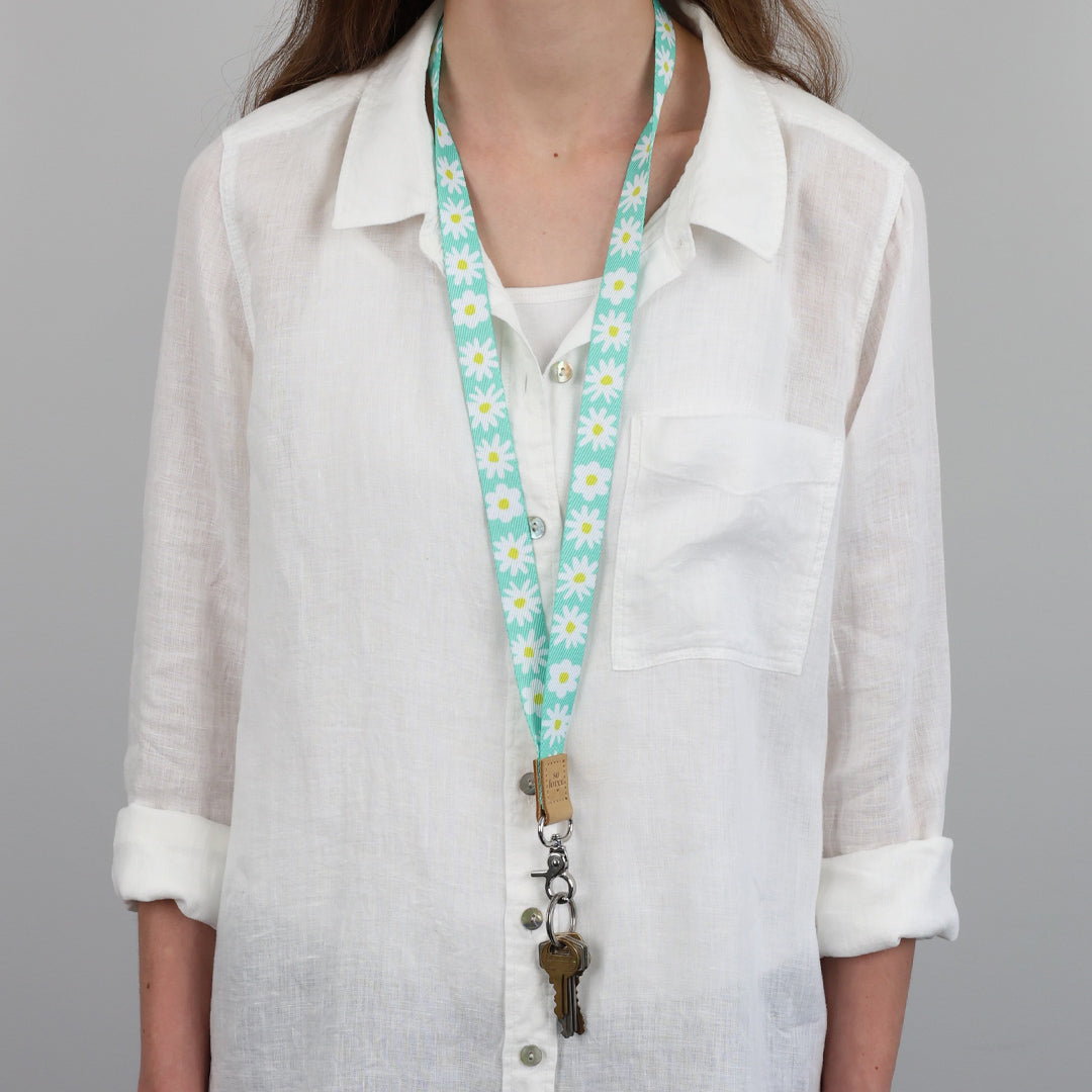 Person wearing a white shirt with a floral lanyard against a gray background