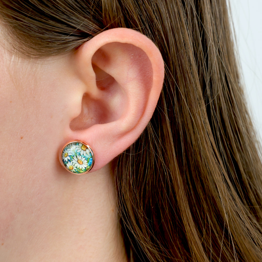 Close-up of an ear wearing a round floral earring with a white background