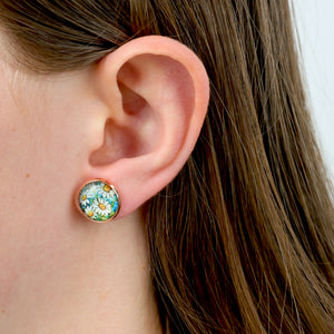 Close-up of an ear wearing a round floral earring with a white background