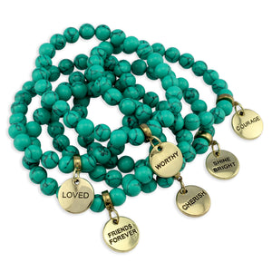 Turquoise beaded bracelets with gold charm tags on a white background