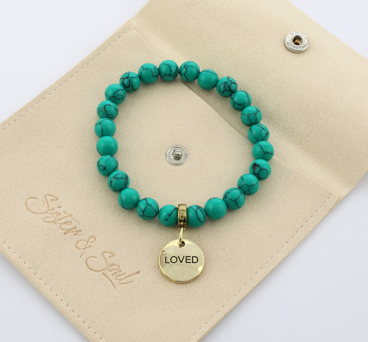 Turquoise beaded bracelet with a gold 'LOVED' charm on a beige card.