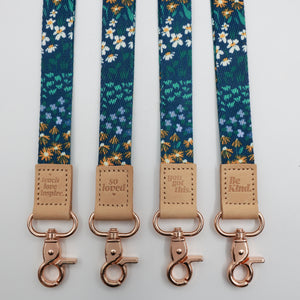 Dark Blue Floral lanyards showing Be Kind, Teach Love Inspire, You Got This and So Loved embossed trims and lobster clasps.