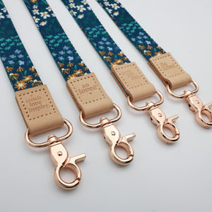 Dark Blue Floral lanyards showing Be Kind, Teach Love Inspire, You Got This and So Loved embossed trims and lobster clasps.