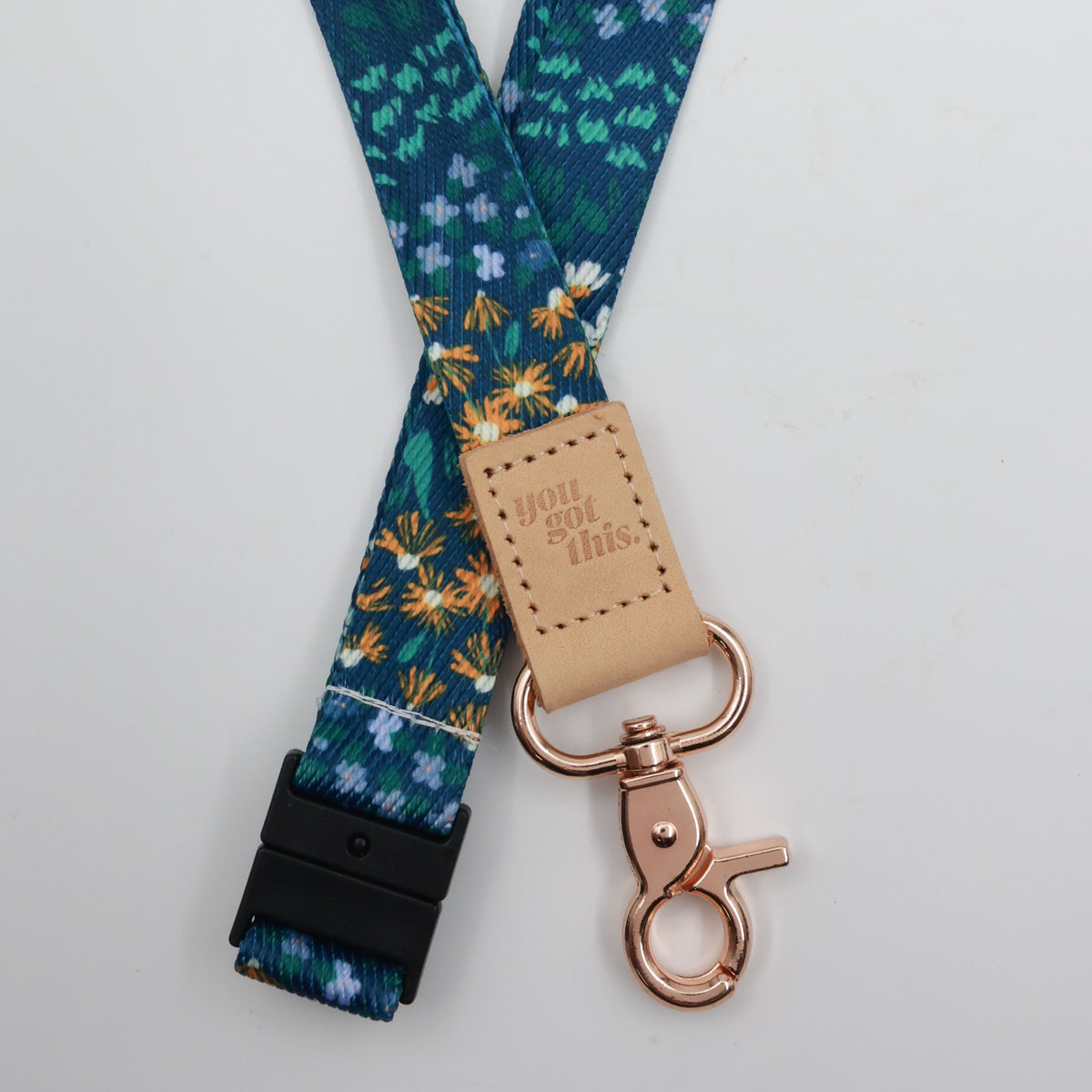 You Got This embossed on a dark blue floral lanyard with tan trim and a lobster clasp.