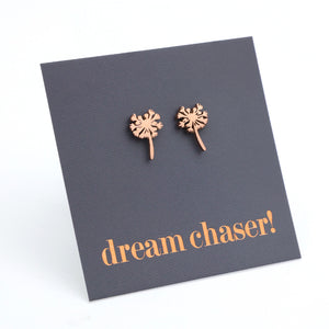 Rose gold dandelion-shaped earrings on a dark gray card with 'dream chaser!' text.